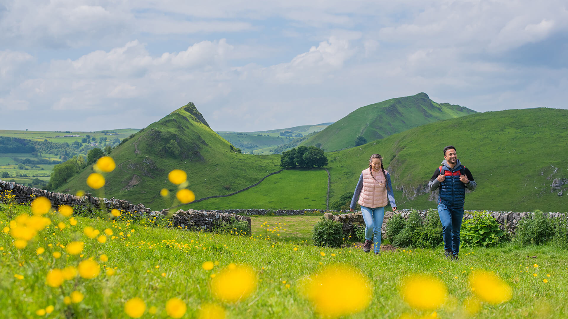 Two people walking through a field in the Peak District